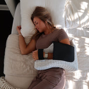 Woman lying on a bed with a Shoulder sleeper pillow