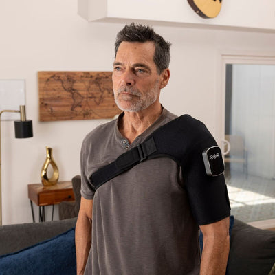 Man wearing a black shoulder brace in a living room setting
